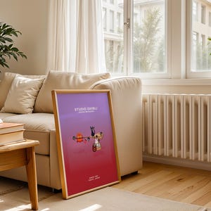 May include: A framed poster with a gradient purple and red background. The poster features cartoon characters and the text "STUDIO GHIBLI" and "SINCE 1985 TOKYO JAPAN". The frame is made of light-colored wood.