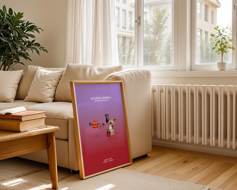 May include: A framed poster with a gradient purple and red background. The poster features cartoon characters and the text "STUDIO GHIBLI" and "SINCE 1985 TOKYO JAPAN". The frame is made of light-colored wood.