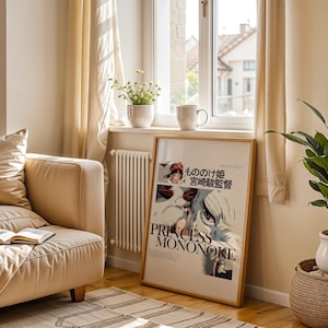 May include: A framed poster of "Princess Mononoke" in a living room setting. The poster is leaning against a wall near a window, with a beige sofa, a potted plant, and a rug. The poster has Japanese text and the title "Princess Mononoke".