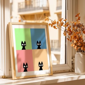 May include: A framed art print featuring four black cat silhouettes against a colorful background of green, blue, pink, and yellow. The artwork is displayed on a windowsill next to a vase of dried orange flowers.