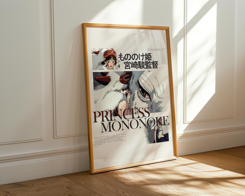 May include: Framed poster featuring the title "PRINCESS MONONOKE" in large, bold letters. The artwork includes illustrations of characters and Japanese text. The frame is a light brown color, and the poster is leaning against a white wall.