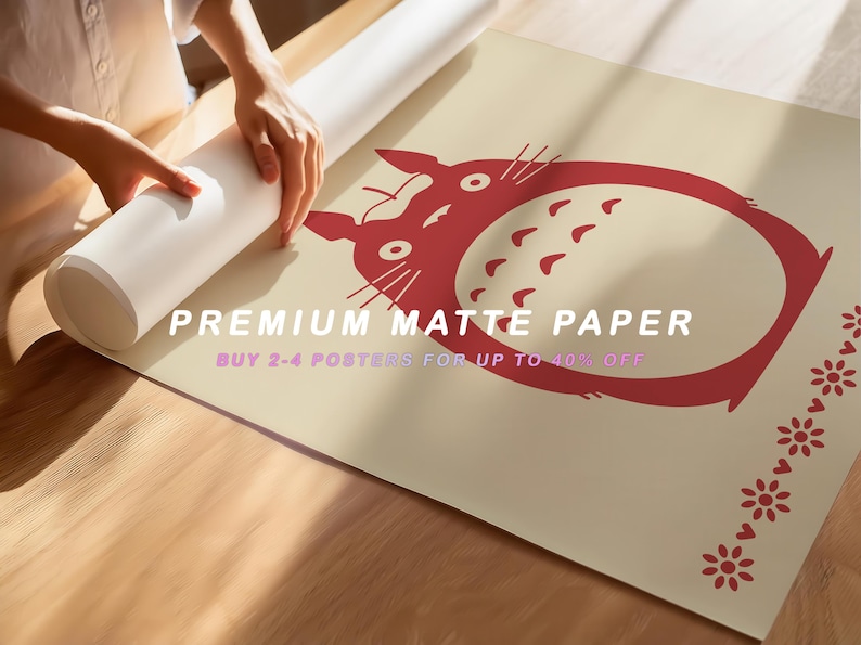 May include: A rolled-up poster featuring a red cartoon character design on a beige background. The text "PREMIUM MATTE PAPER" and "BUY 2-4 POSTERS FOR UP TO 40% OFF" are visible. The poster is being unrolled on a wooden surface.