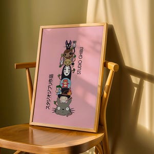 Puede incluir: Un p&oacute;ster rosa enmarcado con personajes apilados de Studio Ghibli. Los personajes incluyen un gato negro, un duende de holl&iacute;n y Sin Rostro. El p&oacute;ster tiene texto japon&eacute;s y las palabras "STUDIO GHIBLI" en blanco.