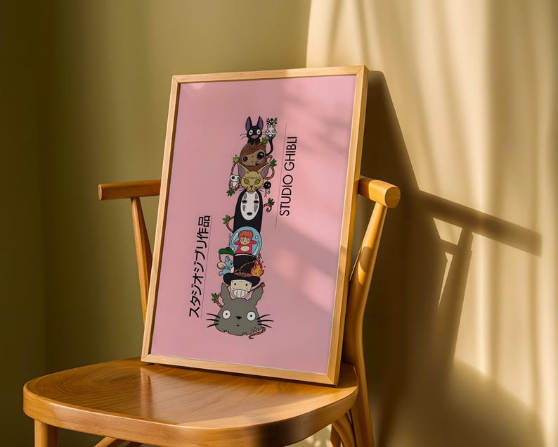 Puede incluir: Un p&oacute;ster rosa enmarcado con personajes apilados de Studio Ghibli. Los personajes incluyen un gato negro, un duende de holl&iacute;n y Sin Rostro. El p&oacute;ster tiene texto japon&eacute;s y las palabras "STUDIO GHIBLI" en blanco.