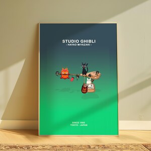 May include: A framed poster featuring Studio Ghibli characters on a gradient green and blue background. The poster includes a broom with black cats, a white cat, and a fiery character. Text at the top reads "STUDIO GHIBLI - HAYAO MIYAZAKI." The bottom text says "SINCE 1985 TOKYO - JAPAN."
