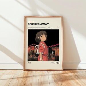 May include: Framed poster featuring the animated film "Spirited Away." The artwork depicts a young girl in a red dress, set against a backdrop of a nighttime scene with lanterns. The poster includes the film's title and the year 2001.