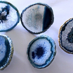 May include: Six agate slices with a white center and a blue rim. The agate slices are smooth and polished.