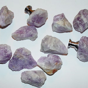 May include: Ten amethyst crystal drawer pulls with silver metal hardware. The amethyst crystals are various shades of purple and have a rough, natural texture.