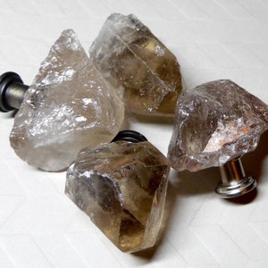 May include: Four clear quartz crystal drawer pulls with silver metal hardware. The crystals are various shapes and sizes.