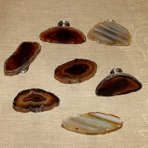 May include: Six agate slice cabinet knobs with silver metal bases. The agate slices are in various shapes and sizes, with brown, white, and gray banding.