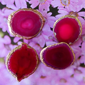 Könnte beinhalten: Vier rosa Achat-Untersetzer mit goldener Umrandung. Die Untersetzer sind rund und haben eine natürliche, organische Form. Sie sind perfekt, um jedem Zuhause einen Hauch von Eleganz zu verleihen.