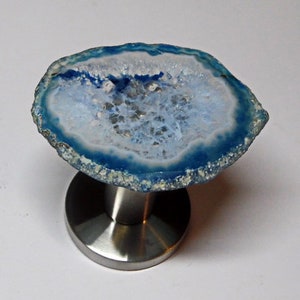 May include: A blue agate geode with a white interior, mounted on a stainless steel base. The geode is a natural stone with a unique pattern and texture.
