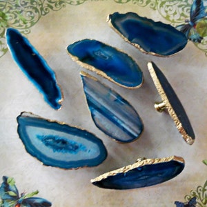 May include: Seven blue agate drawer pulls with gold trim. The agate is a natural stone with a variety of patterns and colors.