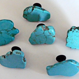 May include: Six turquoise stone cabinet knobs with black metal bases. The stones are all different shapes and sizes.
