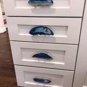 May include: Four white drawers with blue and white agate drawer pulls. The drawers are set against a white background.