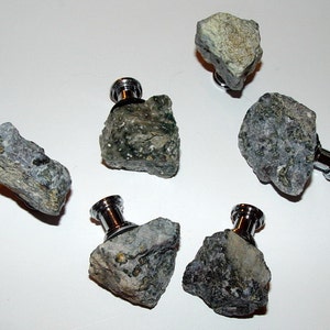 May include: Six rock crystal cabinet knobs with silver metal bases. The knobs are various shades of gray and green with a rough, natural texture.