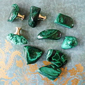 May include: Assortment of green malachite stone cabinet knobs with gold metal hardware. The knobs are in various shapes and sizes.