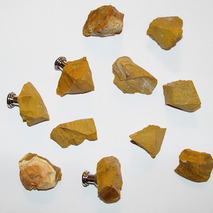 May include: Ten yellow and brown stone knobs with silver hardware. The knobs are irregularly shaped and have a natural, rough texture.