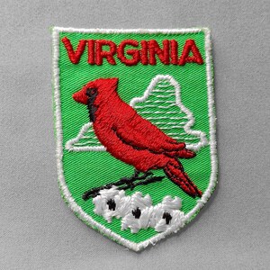 May include: Embroidered patch featuring a red cardinal perched on a branch with white flowers, set against a green shield. The word "VIRGINIA" is stitched in red at the top, with a white border.