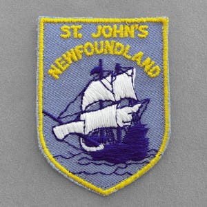 May include: A blue and yellow embroidered patch with the text "St. John's Newfoundland" and a white sailboat with purple accents.