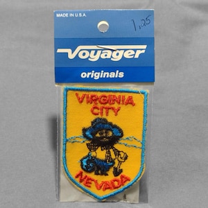 May include: A yellow and blue embroidered patch with the text "Virginia City Nevada" and a cartoon miner holding a pickaxe.