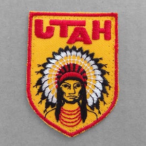 May include: A yellow and red embroidered patch with the word "UTAH" in red lettering and a Native American chief wearing a headdress.
