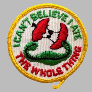 May include: Embroidered patch with the text "I CAN'T BELIEVE I ATE THE WHOLE THING". The patch features a red flower with a black center, a green vine, and a yellow border.