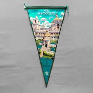 May include: Triangular pennant featuring a detailed illustration of El Escorial, a historic Spanish monastery. The pennant has a teal border and includes text that reads "EL ESCORIAL" and "PATIO DE LOS EVANGELISTAS".