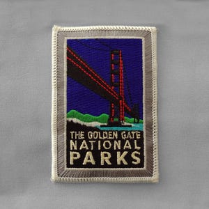 May include: A gray and white embroidered patch with a red and white image of the Golden Gate Bridge. The text "The Golden Gate National Parks" is embroidered in green, red, and white.