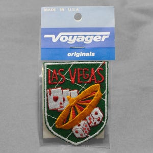 May include: A green and white embroidered patch with the text "LAS VEGAS" in red. The patch features a roulette wheel, playing cards, and dice.