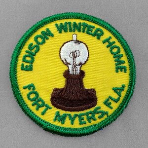 May include: Green and yellow embroidered patch with the text "Edison Winter Home Fort Myers FLA" and a brown light bulb illustration.