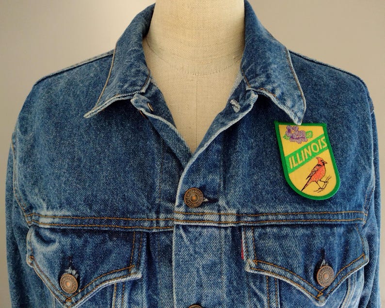 May include: A blue denim jacket with a green and yellow patch featuring a cardinal bird and the word "ILLINOIS".