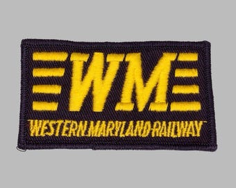 May include: A rectangular patch with the letters "WM" in yellow, above the words "WESTERN MARYLAND RAILWAY" in yellow. The patch has a black background and yellow border.