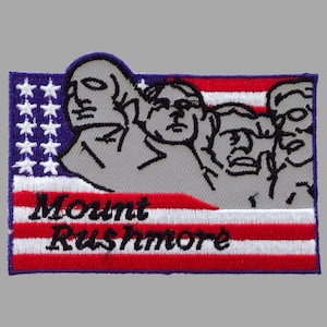 May include: Embroidered patch featuring Mount Rushmore with the text "Mount Rushmore". The design incorporates the American flag with red and white stripes, a blue field of stars, and outlines of the presidents' faces.