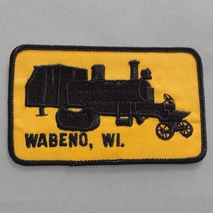 May include: A yellow embroidered patch with a black silhouette of a steam locomotive and the text "WABENO, WI".