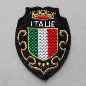 May include: Embroidered patch featuring the Italian flag colors: green, white, and red. The patch is shield-shaped with the word "ITALIE" in white. Gold-colored embroidery outlines the shield and crown.