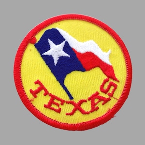 May include: A yellow and red embroidered patch with a blue and white Texas flag and the word "TEXAS" in red.
