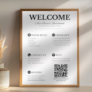 May include: A framed welcome sign for Azie Basics Apartment. The sign includes house rules, check-out instructions, contact information, Wi-Fi details, and a QR code to visit the website. The sign is in a wooden frame.