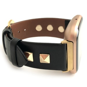 May include: A black leather watch band with gold studs and a rose gold watch face.