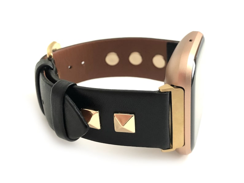 May include: A black leather watch band with gold studs and a rose gold watch face.