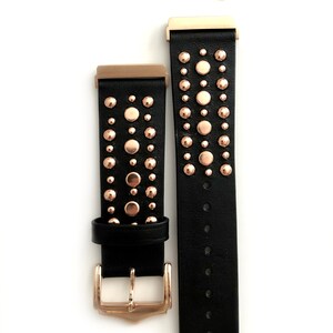 May include: Black leather watch band with rose gold studs and a rose gold buckle. The band is shown with two spring bars.