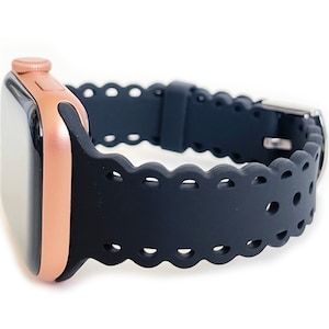 May include: A black silicone Apple Watch band with a scalloped edge and a rose gold Apple Watch.