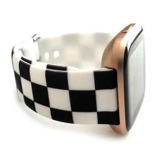 May include: A rose gold smartwatch with a black and white checkered silicone band.