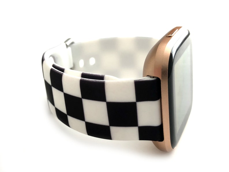 May include: A rose gold smartwatch with a black and white checkered silicone band.