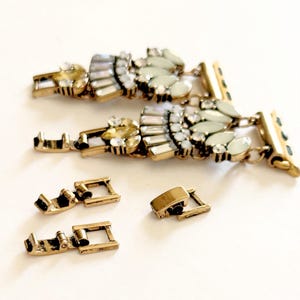 May include: Two gold-tone watch bands with a crystal and pearl design. The bands are connected to gold-tone watch clasps. There are four additional gold-tone watch clasps.