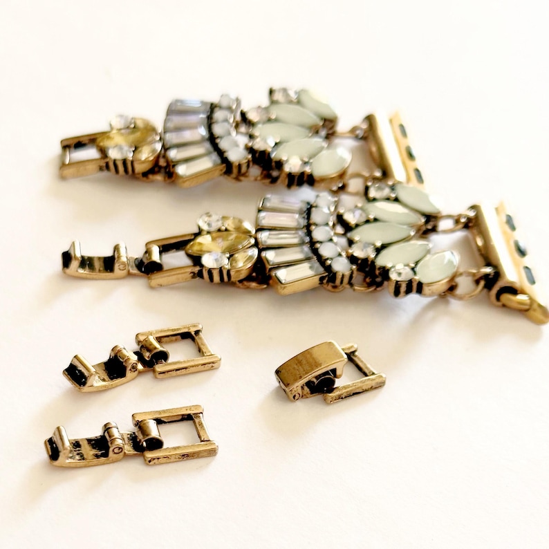 May include: Two gold-tone watch bands with a crystal and pearl design. The bands are connected to gold-tone watch clasps. There are four additional gold-tone watch clasps.