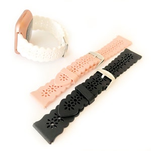 May include: Three silicone watch bands with a decorative floral pattern. The bands are white, pink, and black.