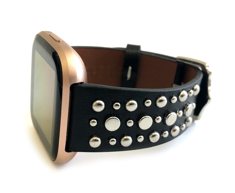 May include: A black leather watch band with silver studs. The band is designed for a rose gold smartwatch.
