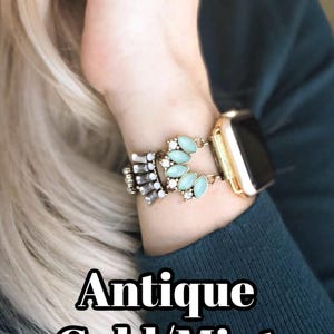 May include: A gold and mint green watch band with a decorative design featuring rhinestones and oval-shaped stones.  Antique Gold/Mint