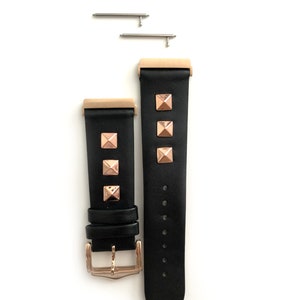May include: Black leather watch band with rose gold accents and pyramid-shaped studs. The band has a buckle closure and comes with two spring bars.